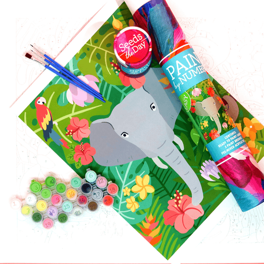 Colorful elephant-themed DIY paint-by-number kid's craft kit with paints, brushes, and canvases on a tropical floral background.