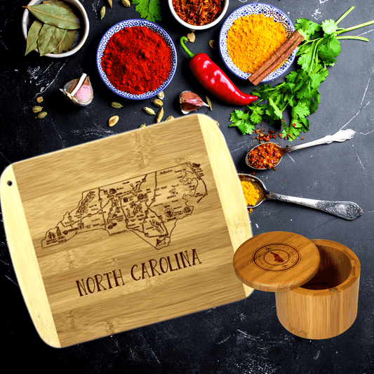 Wooden cutting board showcasing North Carolina's state outline, surrounded by an assortment of colorful spices, herbs, and cooking ingredients on a dark background.
