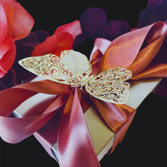 Ornate gold butterfly-shaped decoration with a vibrant orange ribbon on a colorful floral arrangement.
