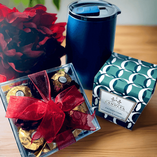 Blue gift canister, red floral arrangement, and boxed chocolates - an elegant custom gift set featuring premium drinkware and sweets.