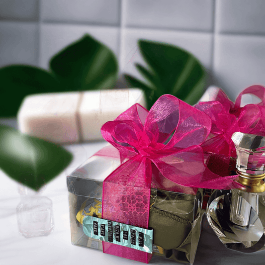 Colorful gift boxes with pink and blue bows, filled with bath and body products, displayed on a reflective surface.