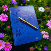 Thumbnail for Blue notebook with floral design and 'Amazing Grace' text, placed on a bed of flowers.