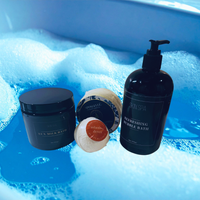 Thumbnail for Bath products including a jar, bottle, and bath bombs in a bathtub filled with bubbles.