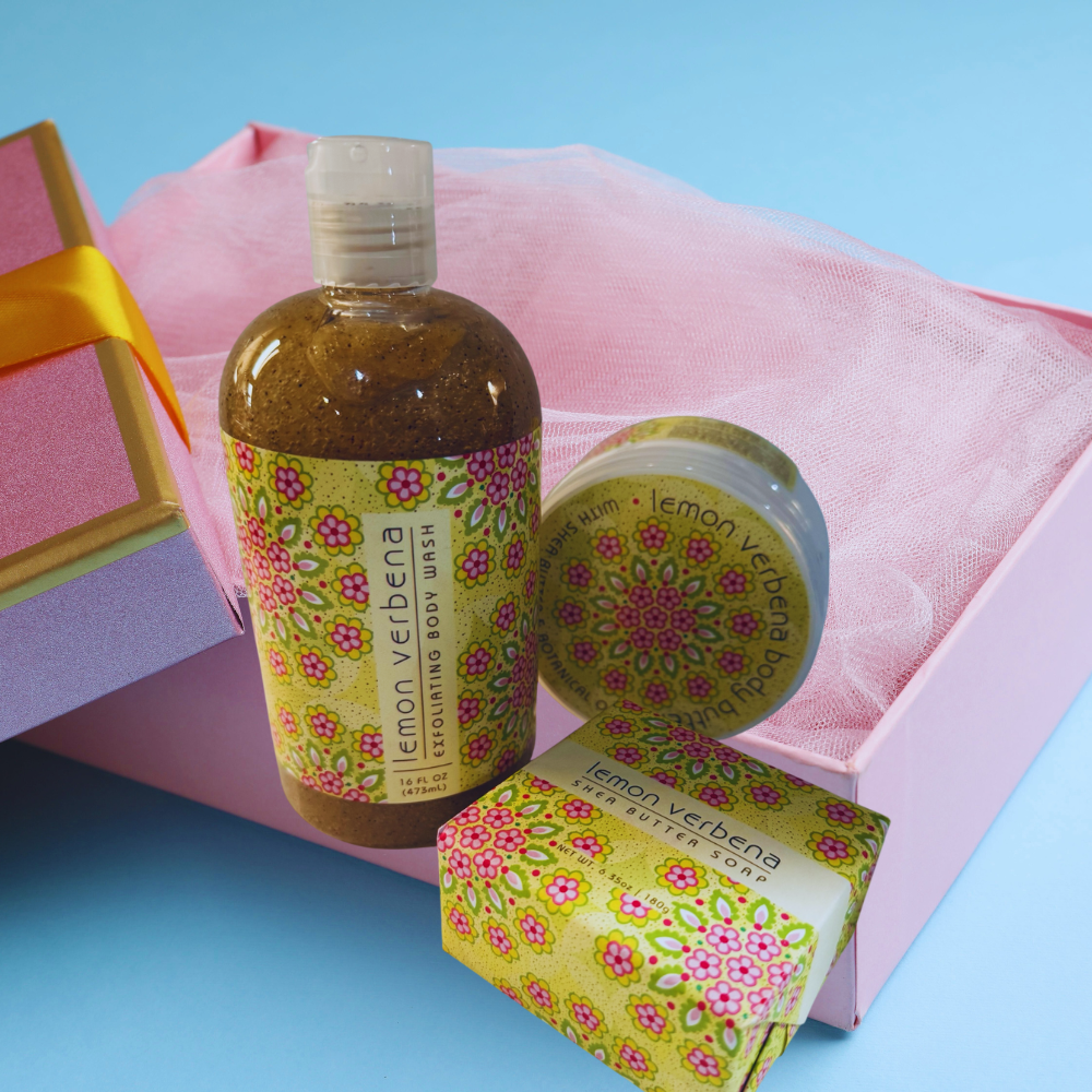 Lemon Verbena bath products including a bottle, bar of soap, and body wash on a pink mesh bag with a blue background.