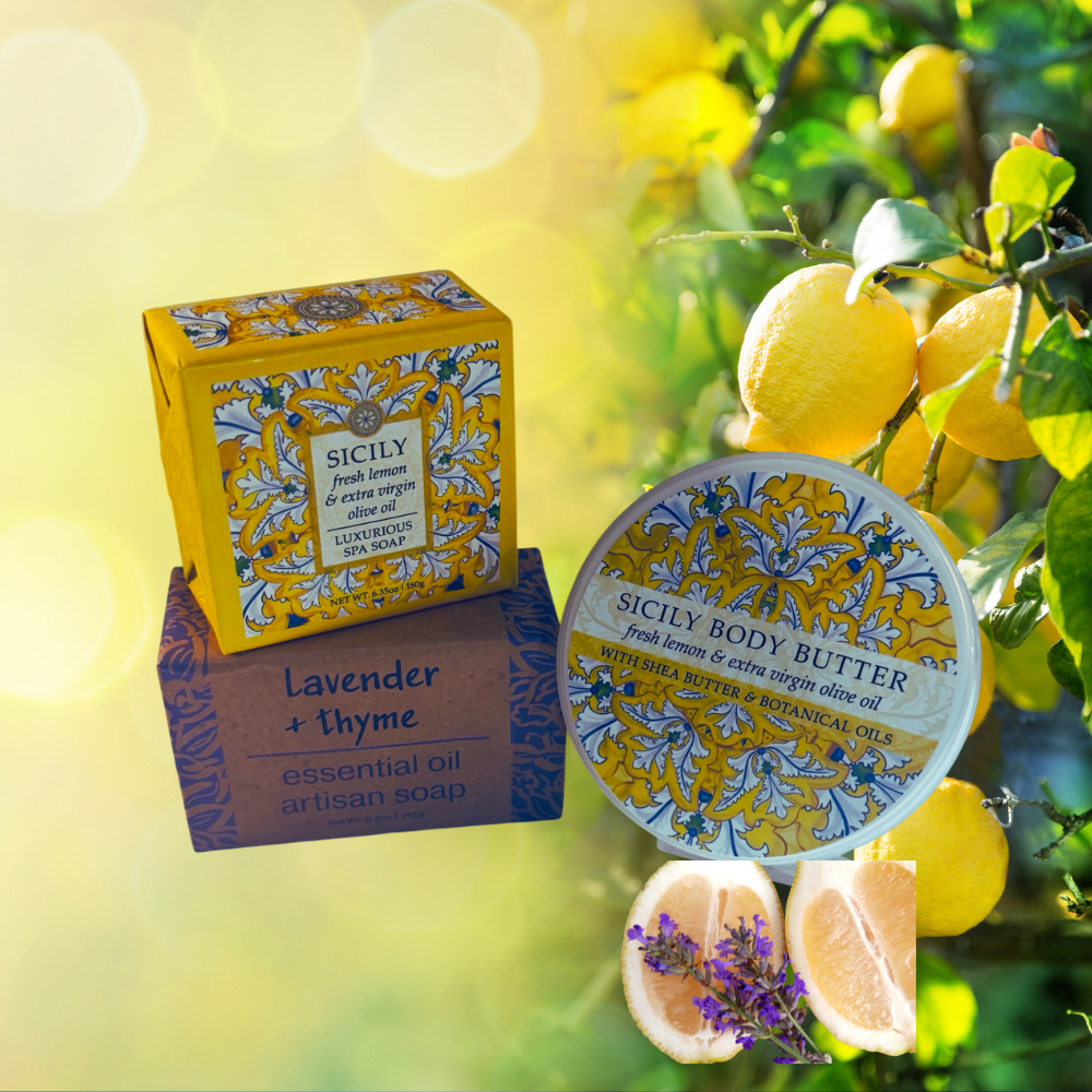 Sicily brand body butter and soap products arranged on a bright yellow-and-green background with lemon imagery. The set includes a yellow patterned Sicily box, a brown box labeled Lavender + thyme artisan soap, a round tin of Sicily Body Butter, and lemon slices with lavender sprigs.