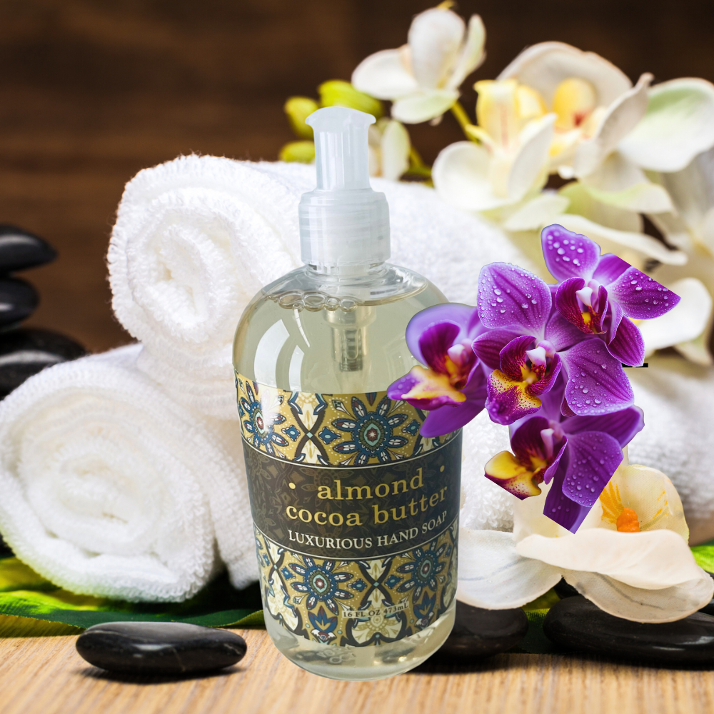 Bottle of almond cocoa butter hand soap with flowers and towels on a wooden surface