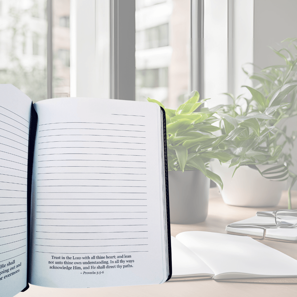 Open book on a desk with a plant and window in the background