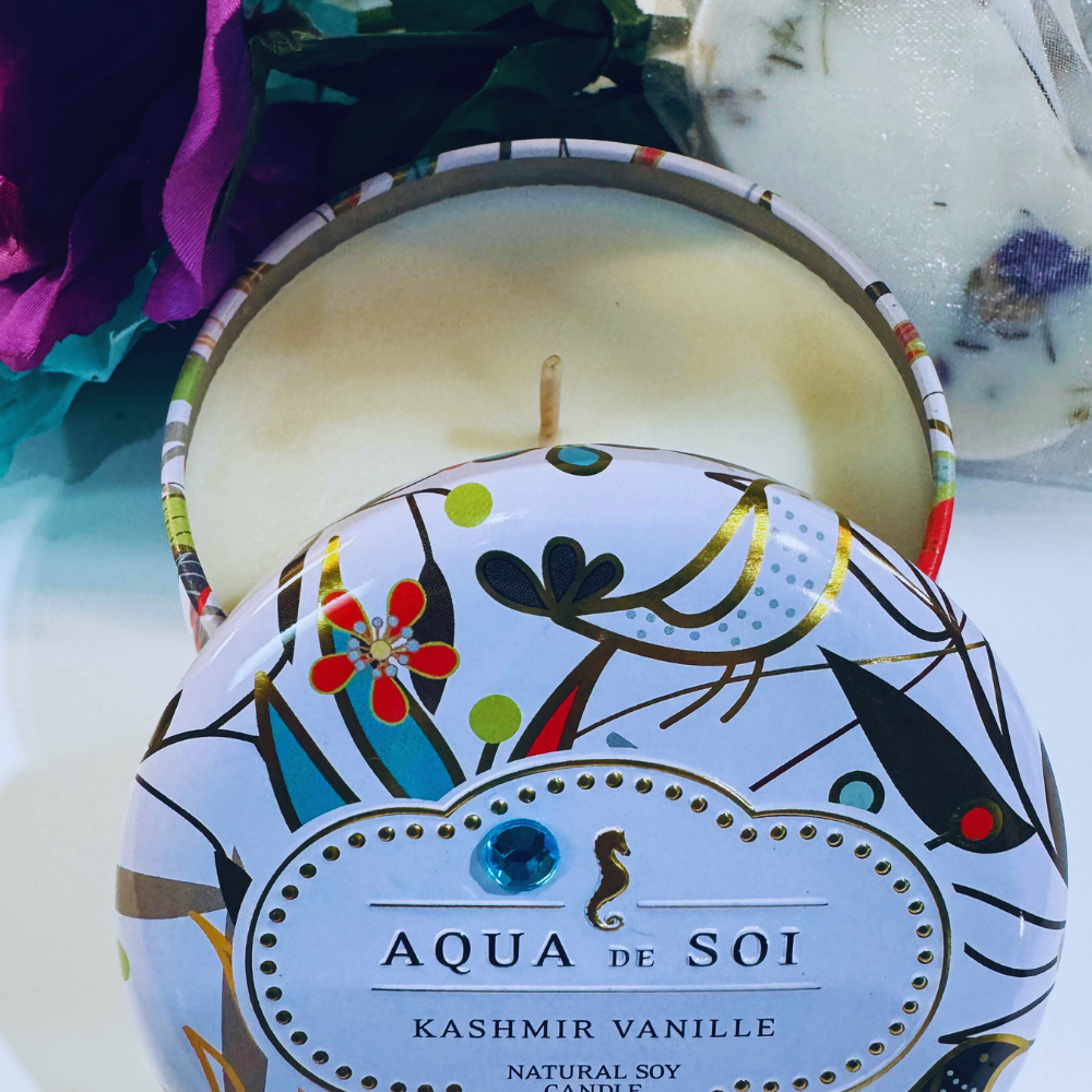 Candle with 'Aqua de Soi' label and floral design on a white background