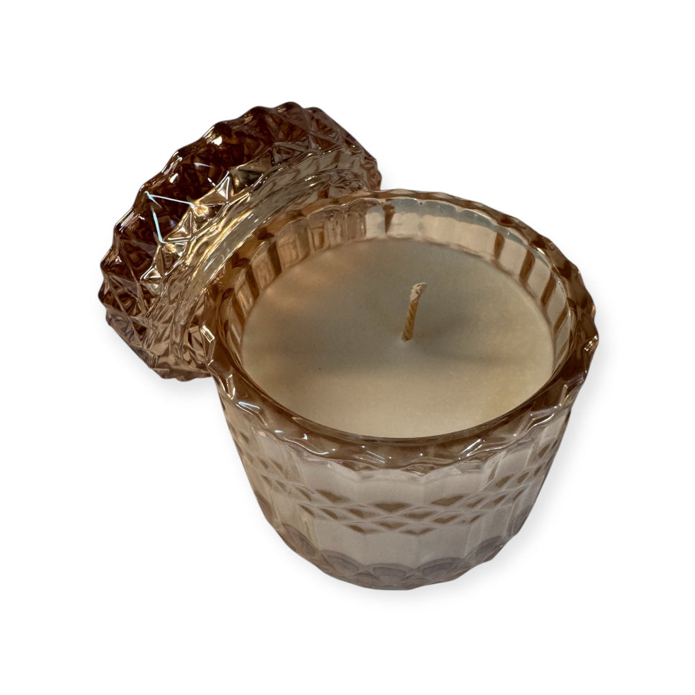 Decorative candle in a pink textured glass holder on a white background