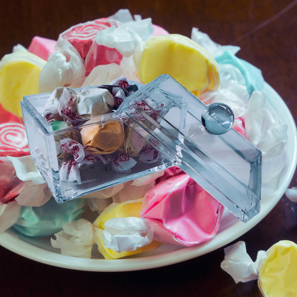 Clear candy cube with assorted candies on a bed of colorful candy.