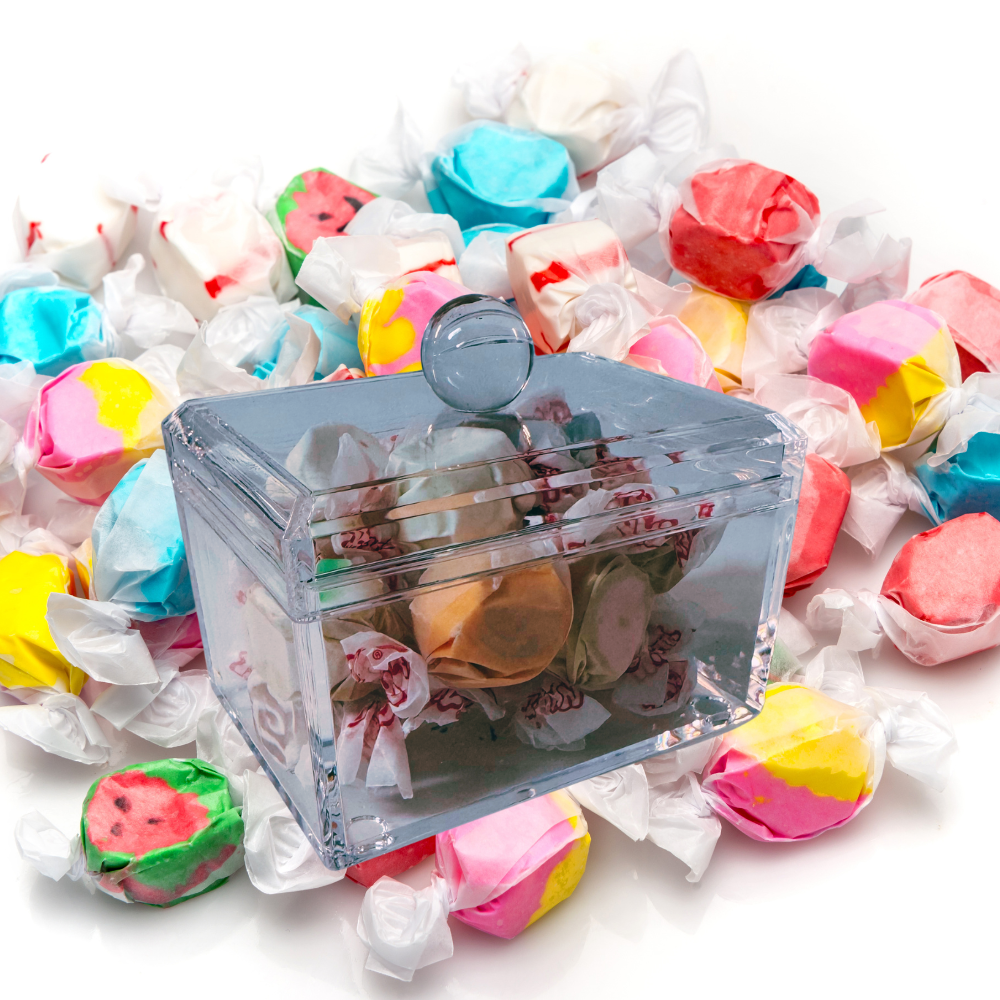 Clear candy container surrounded by colorful taffy on a white background