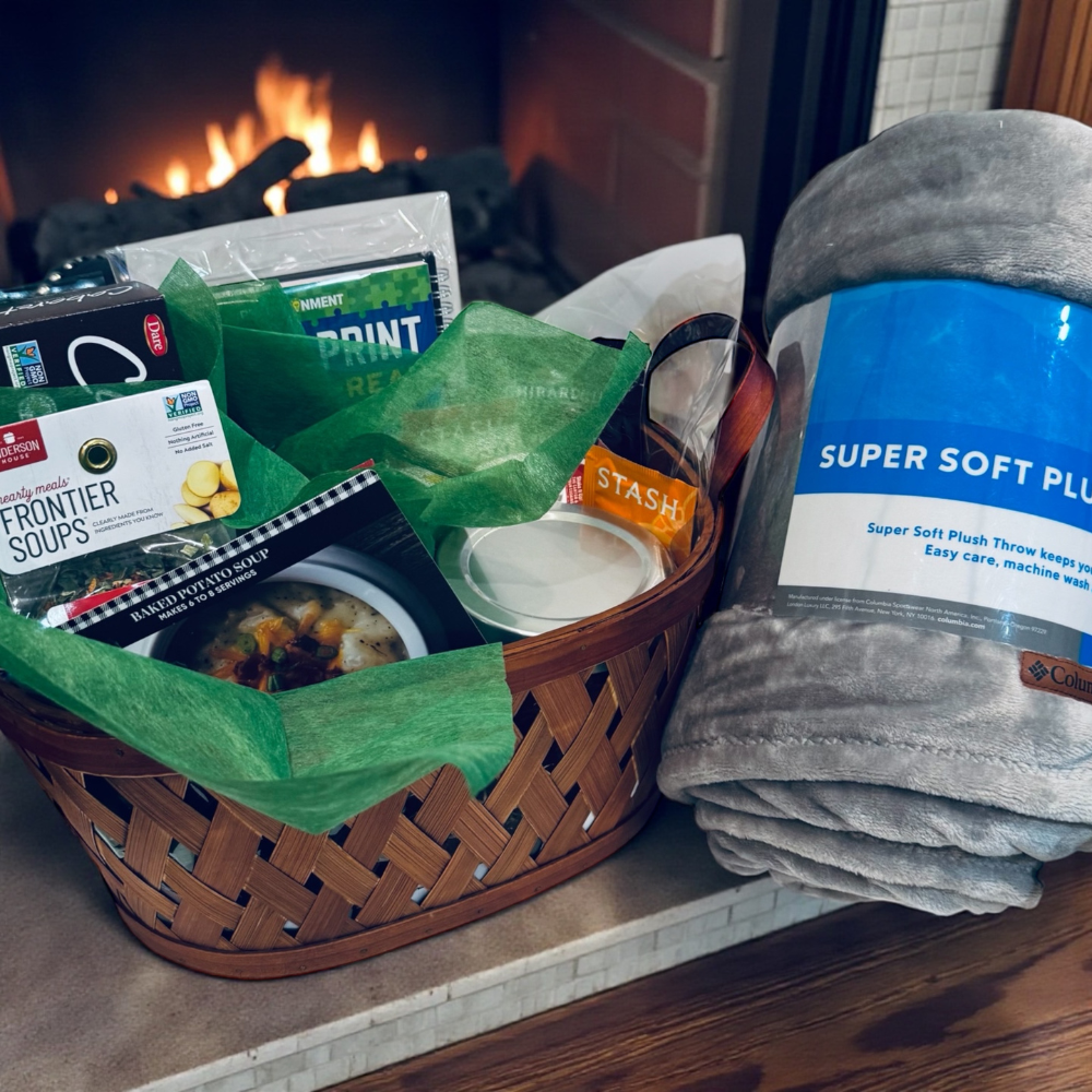 Basket with food items and a blanket on a surface in front of a fireplace
