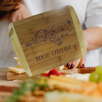 Thumbnail for Wooden cutting board with engraved map of North Carolina and 'North Carolina' text, held by a person.