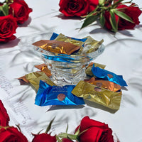 Thumbnail for Godiva chocolate bars in colorful wrappers with red roses on a white fabric background