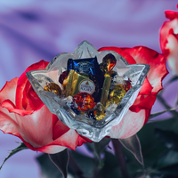 Thumbnail for Glass bowl with chocolates on a red rose against a blurred background