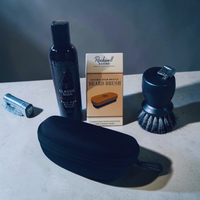 Thumbnail for Men's grooming products including a face wash bottle, beard brush, and case on a gray surface.