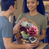 Thumbnail for Woman holding a gift basket with flowers and a plant, interacting with a man.