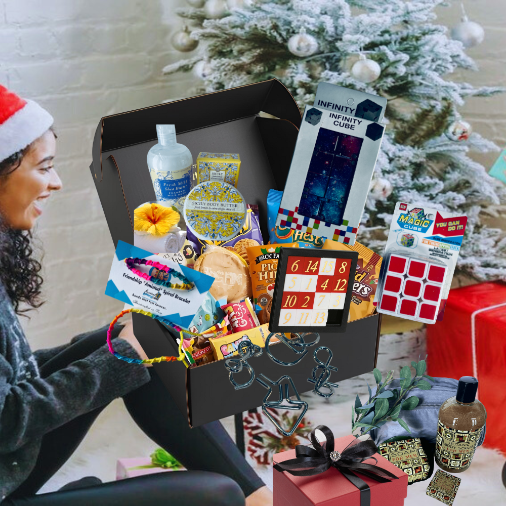 Person opening a gift box filled with various items in front of a decorated Christmas tree.