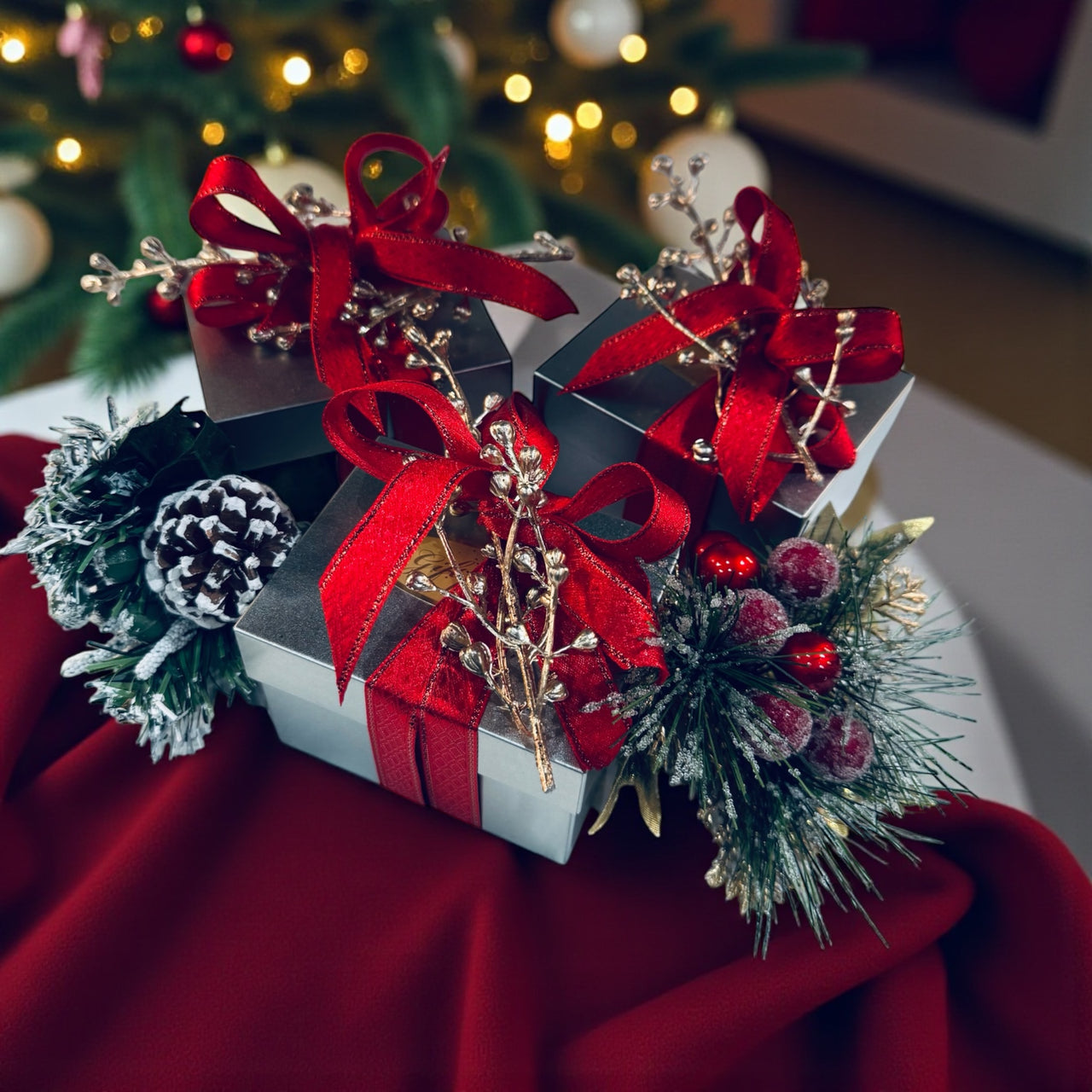 Decorative gift box with red ribbons and Christmas decorations on a red surface.