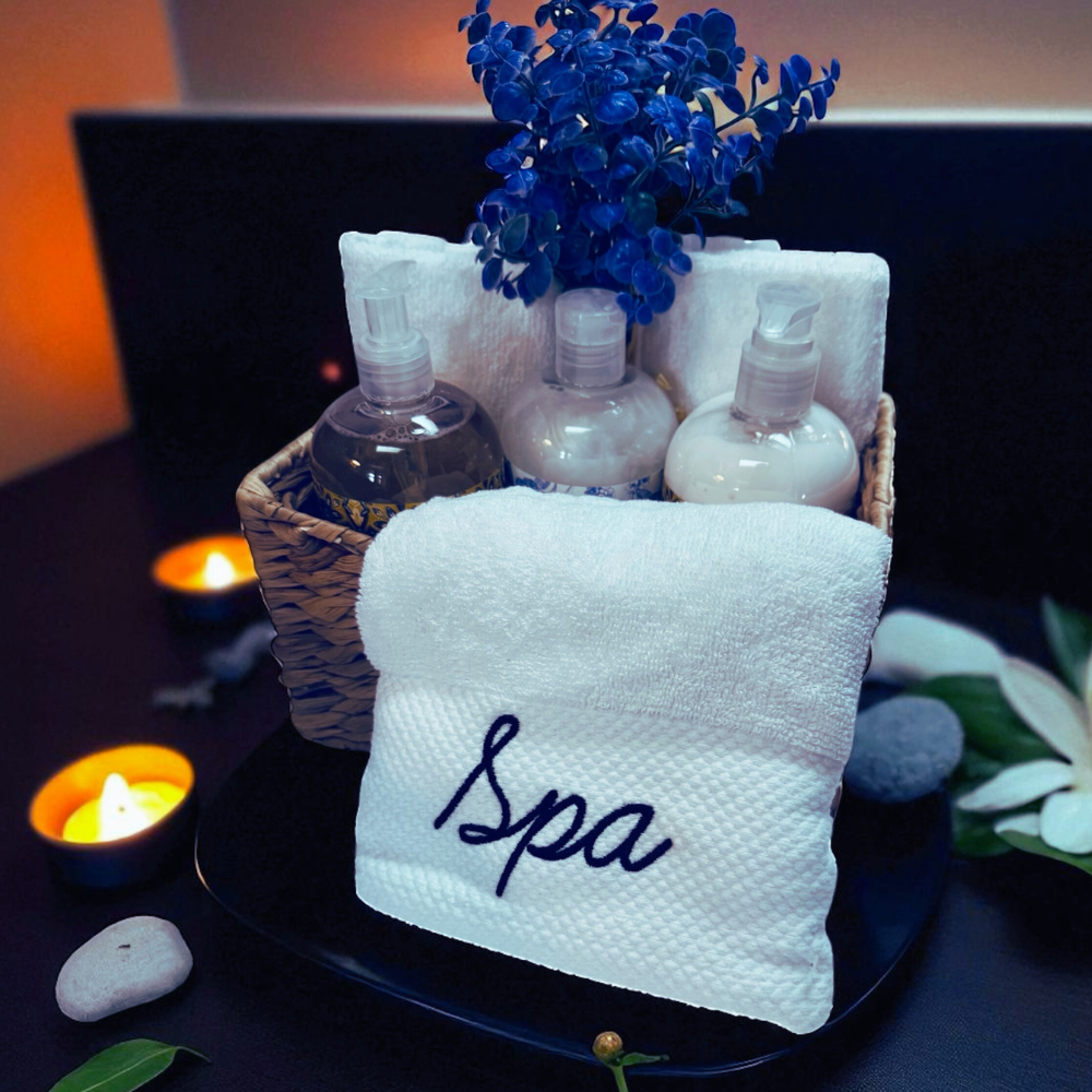 Spa-themed setup with towels, bottles, and flowers on a dark surface.