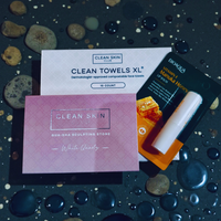 Thumbnail for Cosmetic products including Clean Skin Club towels and a gua sha stone on a dark surface with water droplets.