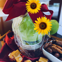 Thumbnail for Gift basket with sunflowers, green apple, and snacks on a red fabric