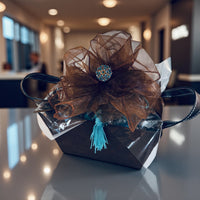 Thumbnail for Decorative gift box with brown organza bow and blue tassel on a reflective surface.