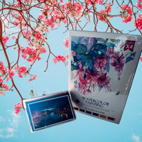 Thumbnail for Packaging of watercolor painting paper with cherry blossoms and a scenic card against a blue sky.