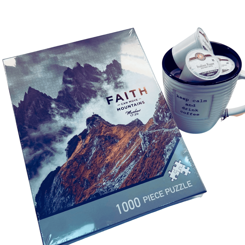 Jigsaw puzzle box with mountain design and a mug with a product inside on a white background