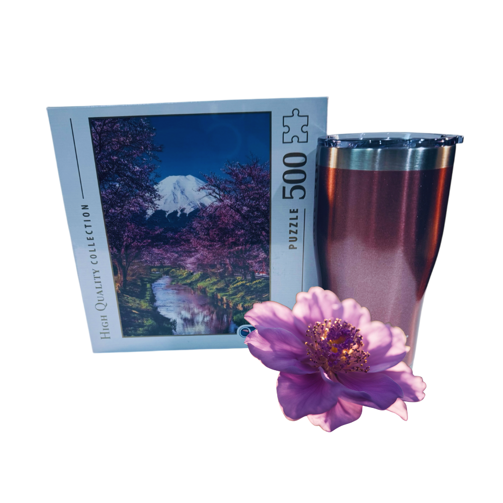 Jigsaw puzzle box with a scenic design, pink flower, and metallic cup on a white background