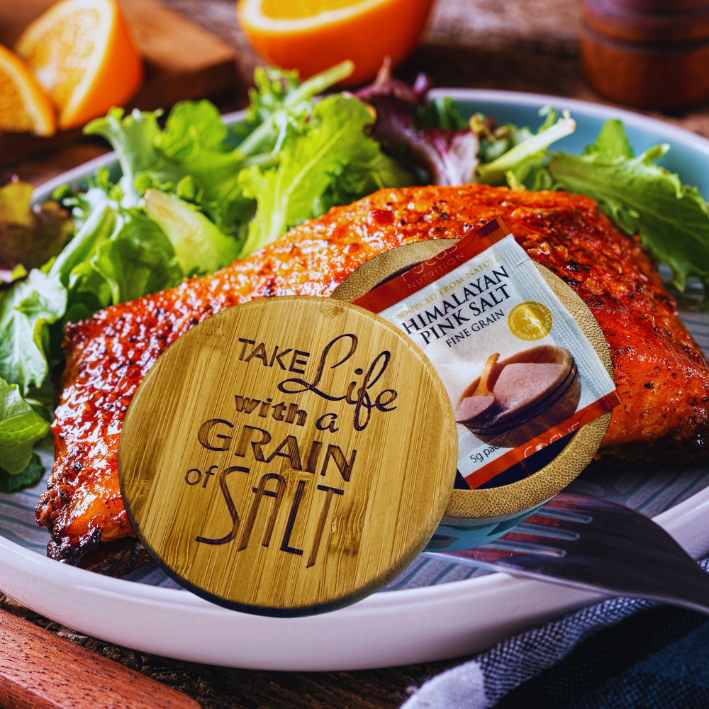 Bamboo salt cellar with text on a plate of grilled fish and salad