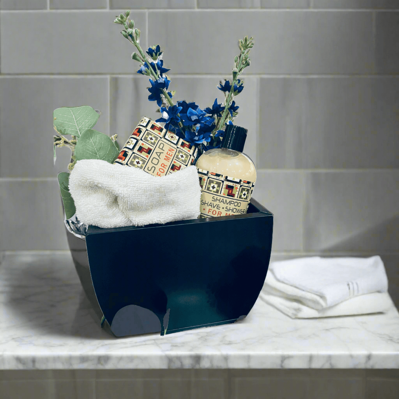 Elegant men's toiletry set with blue flowers, towels, and grooming products displayed on a marble surface.