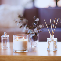 Thumbnail for Candle, diffuser, and small bottle on a wooden surface with blurred background
