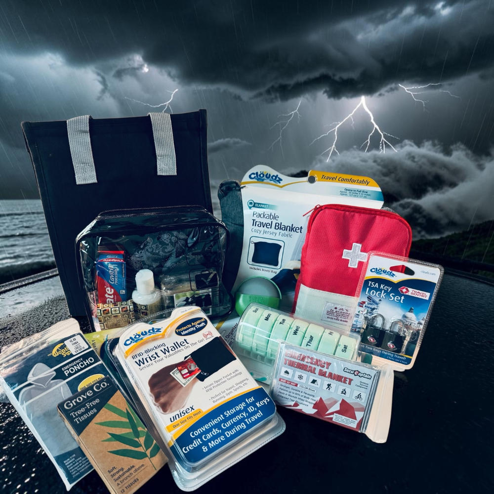 Collection of emergency supplies including a first aid kit, travel blanket, and poncho against a stormy background.
