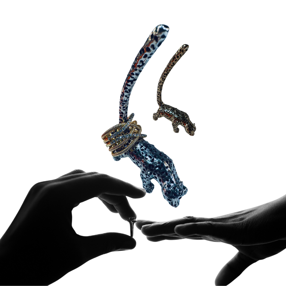 Decorative object resembling a snake with gemstones held between two hands on a white background