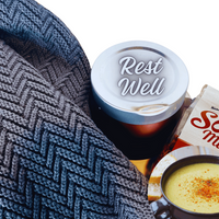 Thumbnail for Cup of coffee with 'Rest Well' lid, wrapped in a blanket, next to a bowl of soup.