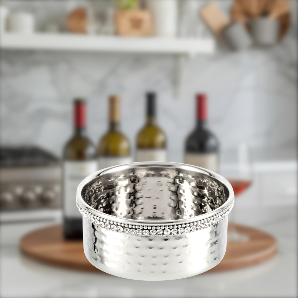 Silver decorative bowl on a wooden coaster with wine bottles in the background