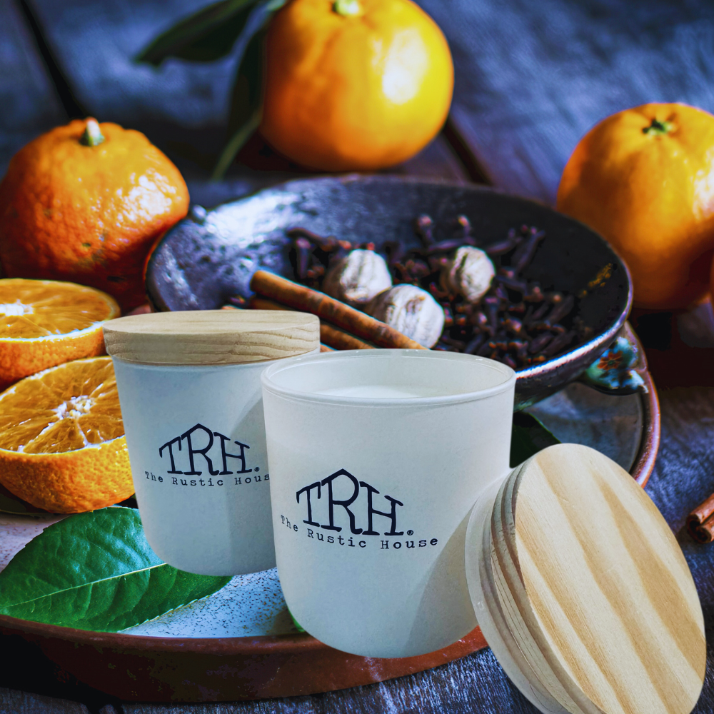 Two white ceramic cups with wooden lids on a table with oranges and spices.