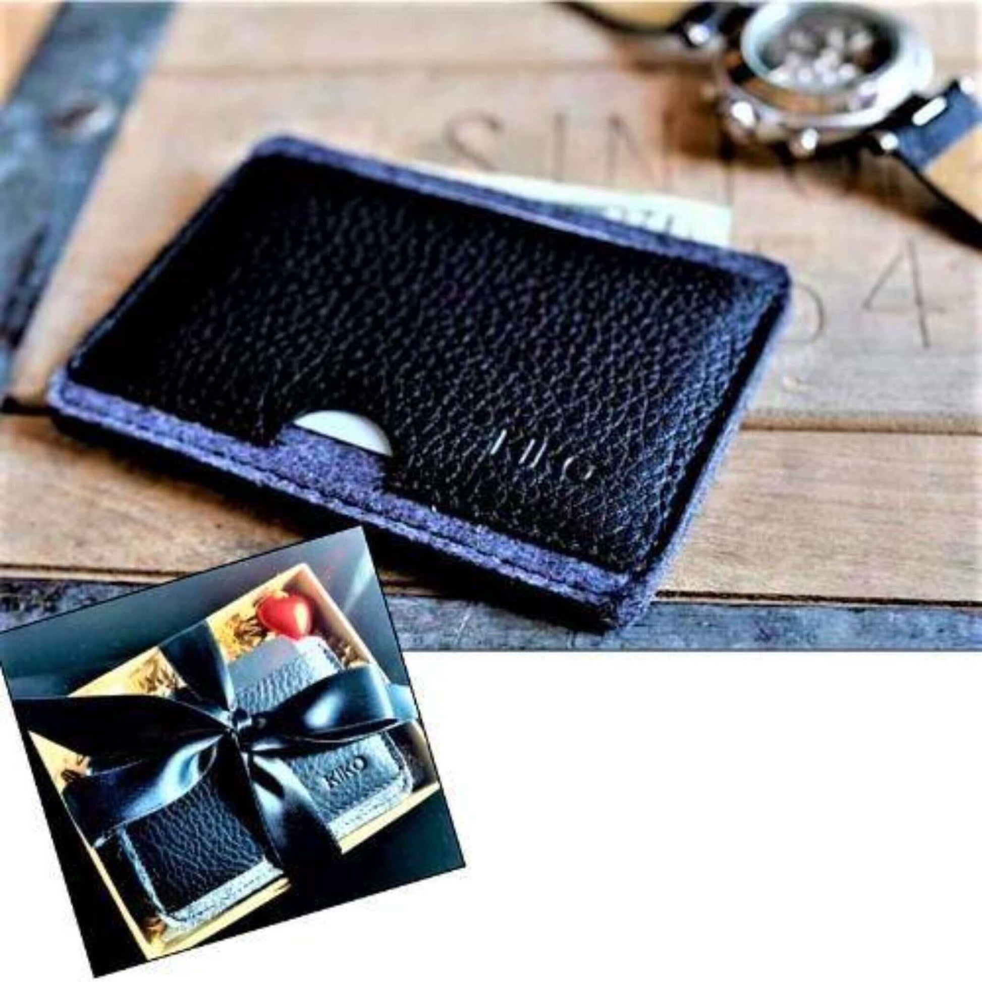Compact black leather wallet with card slots on a wooden surface, accompanied by a gift box.
