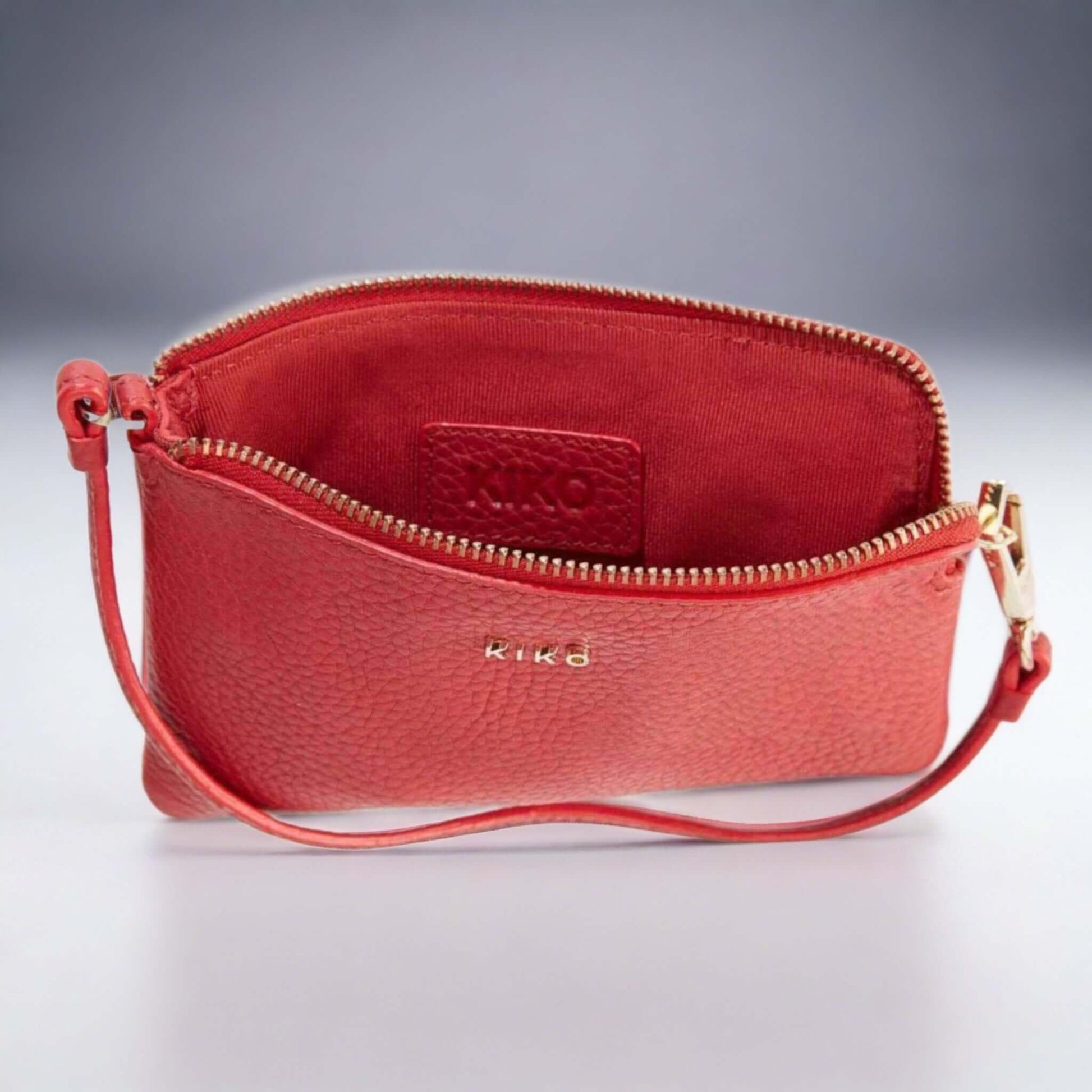 Compact red leather wristlet with zip compartments and gold-tone hardware.